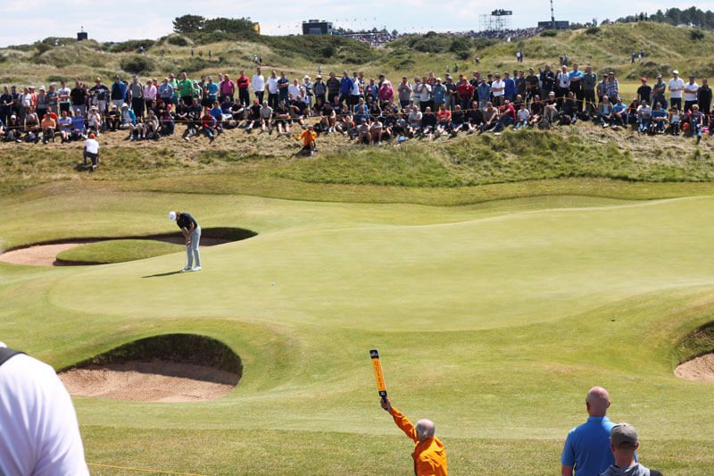 A crowd watches as the golfer waves to his fans.