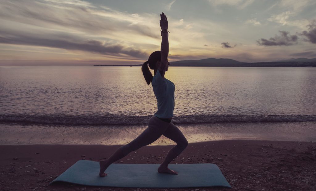 A woman is doing yoga on the beach