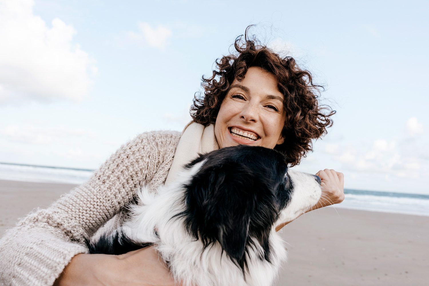 A woman holding her dog on the beach