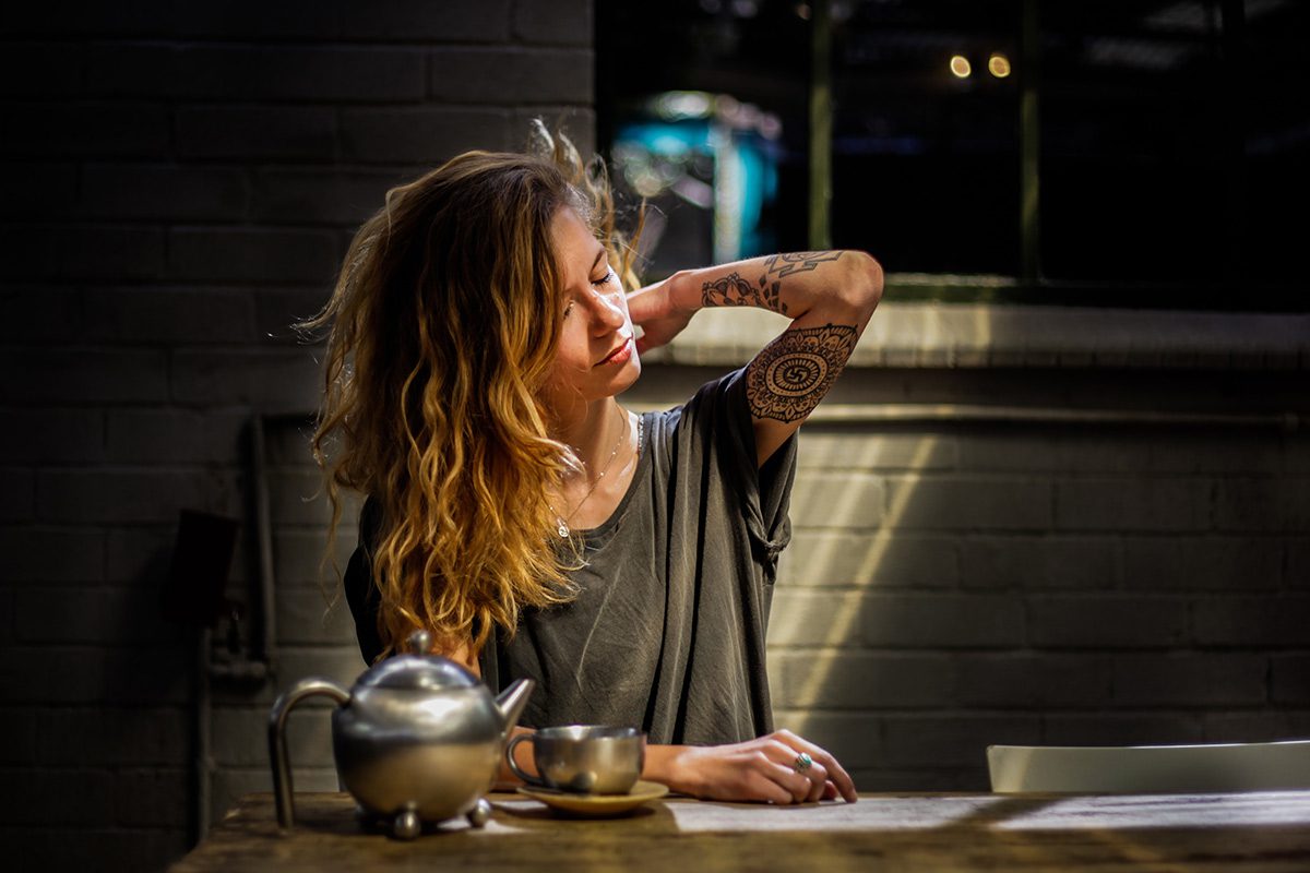 A woman sitting at a table with her hand on her face.