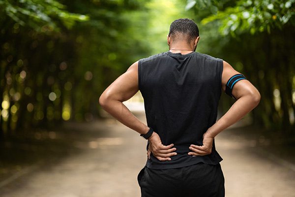 A man with his hands on the back of his lower back.