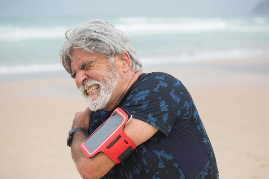 Myofascial Pain Syndrome: Symptoms and Treatments Regenerative Medicine & Orthopedics Miami Senior man with shoulder pain on beach.